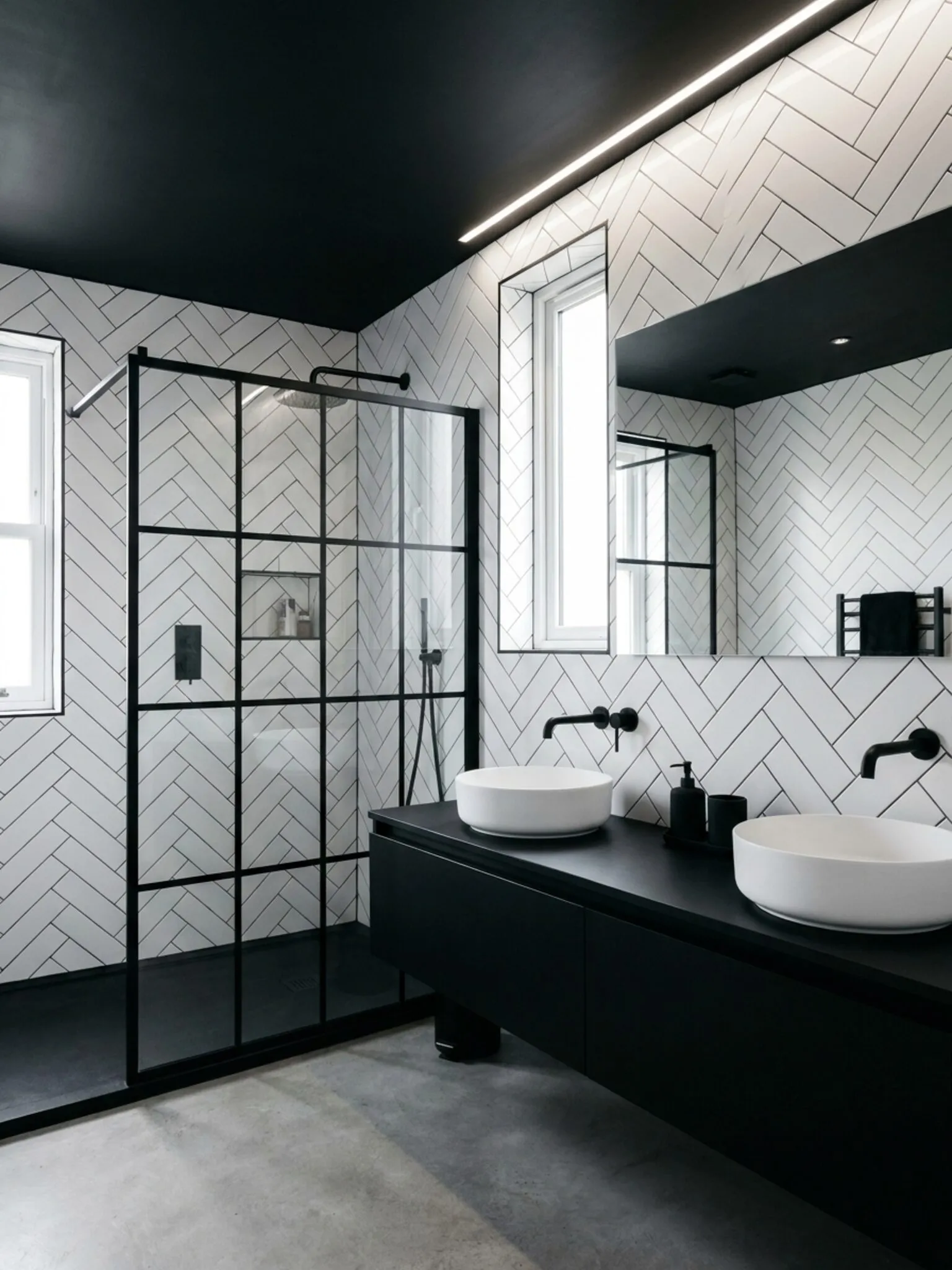 Monochrome shower room with white herringbone metro tiling, black feature ceiling with LED strip and twin countertop basins
