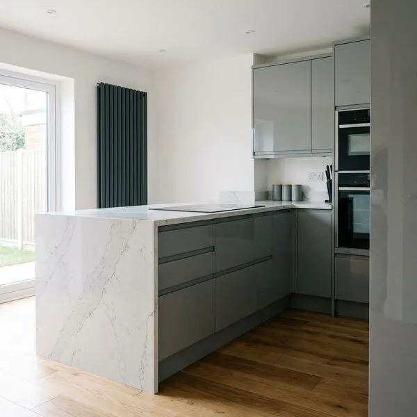 Grey gloss handleless kitchen with marble-effect peninsula worktop and anthracite designer radiator